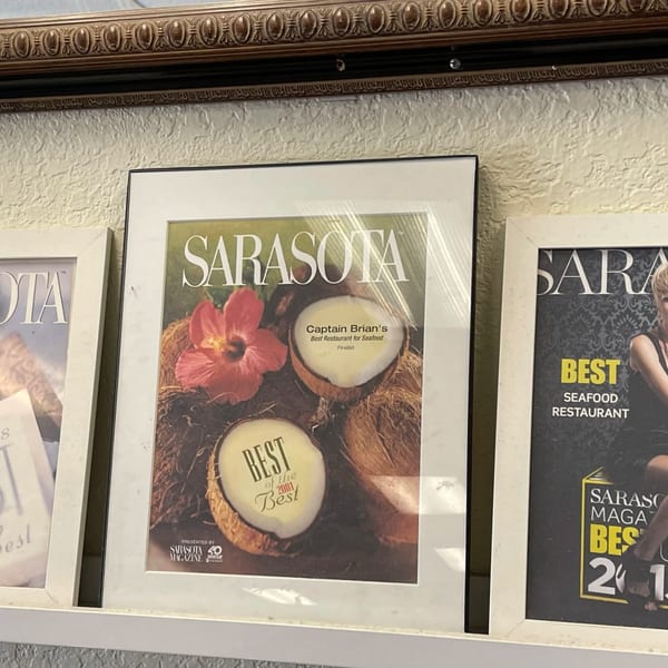 Framed Sarasota Magazine cover featuring coconuts, a hibiscus, and "Captain Brian's Best Restaurant for Seafood" text.