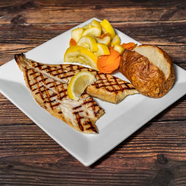 Grilled fish with lemon, baked potato, and sautéed squash and carrots on a white plate.