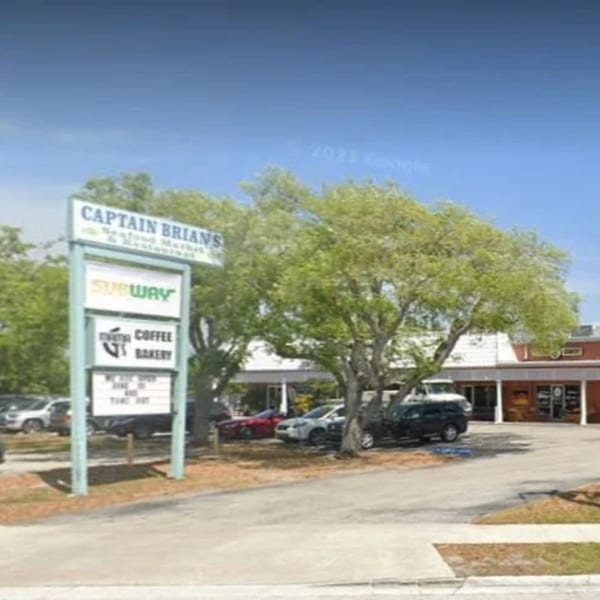 Exterior view of Captain Brian's Seafood Market & Restaurant sign, with trees and parked cars.
