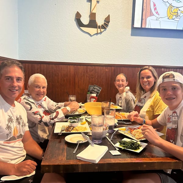 Five people smiling at a table, enjoying seafood dishes at Captain Brian's restaurant.