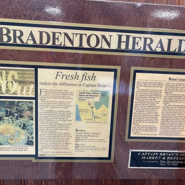 A framed newspaper article from the Bradenton Herald reviewing Captain Brian's Seafood Market & Restaurant.